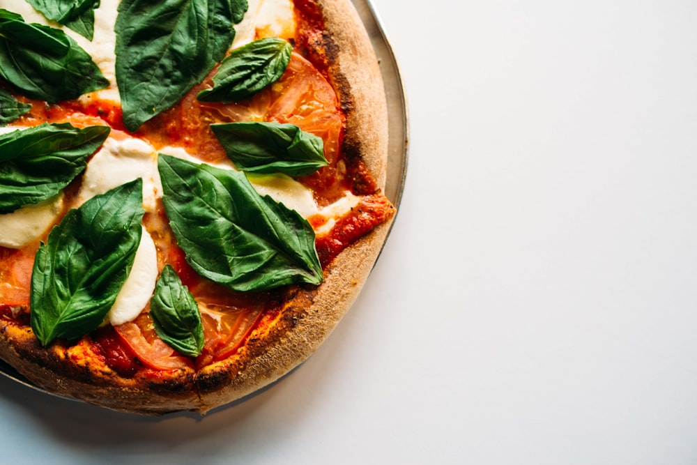 pizza with green leaves on white ceramic plate