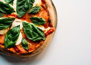 pizza with green leaves on white ceramic plate