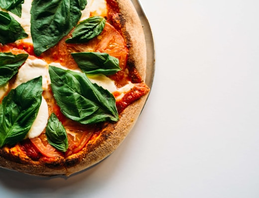 pizza with green leaves on white ceramic plate