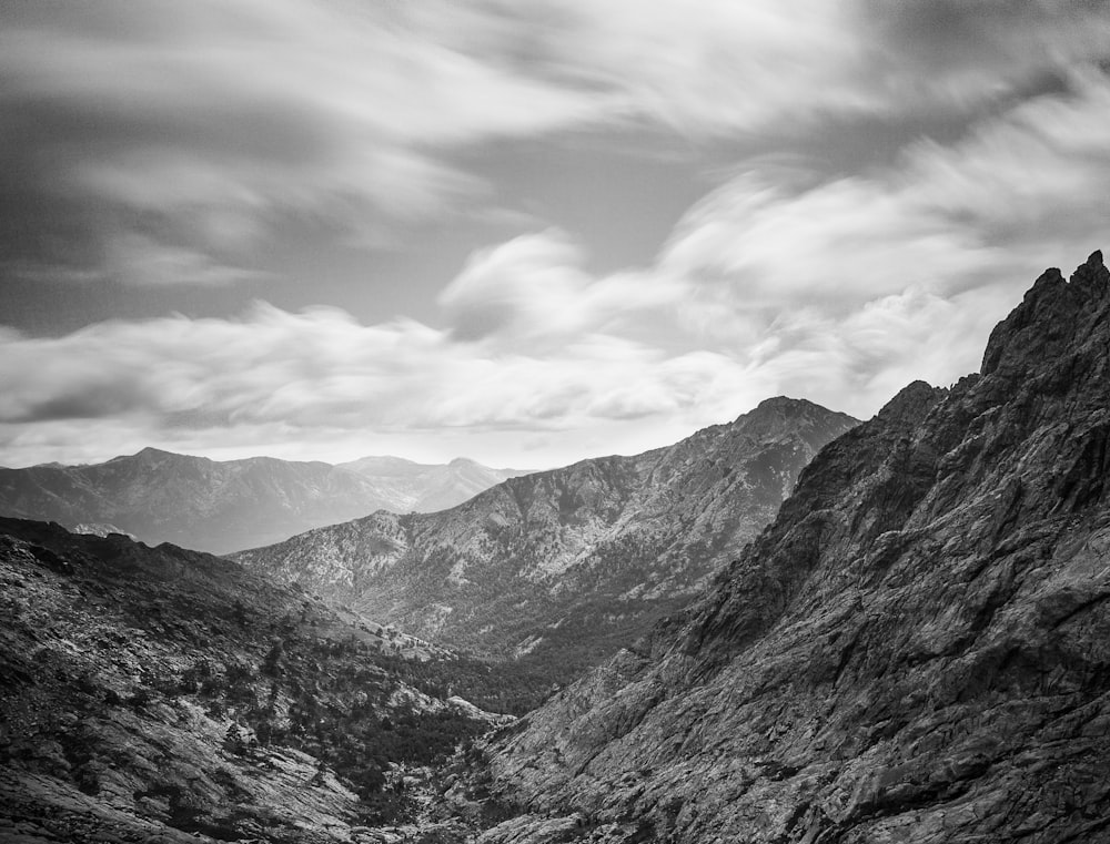 grayscale photo of mountains under cloudy sky