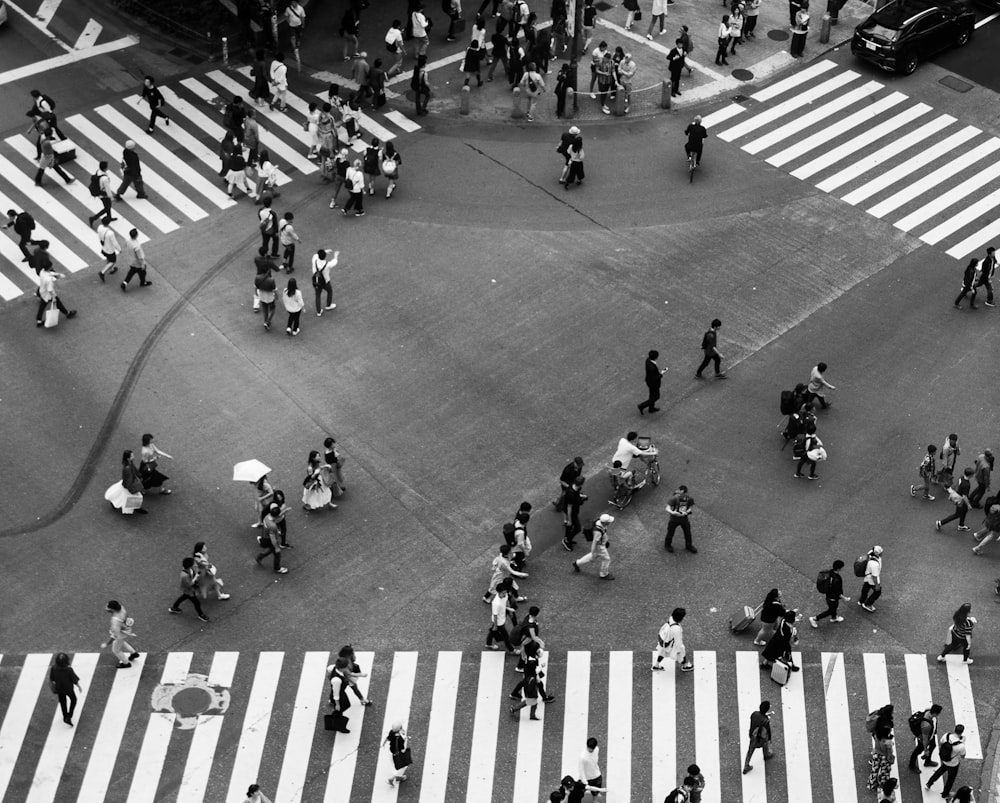 persone che camminano per strada nella fotografia in scala di grigi