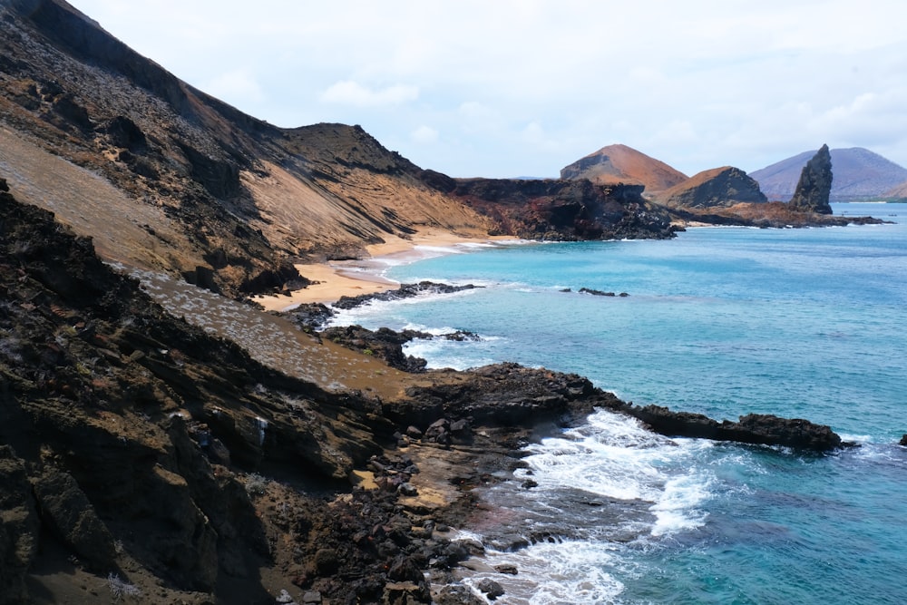 Montañas marrones y verdes junto al cuerpo de agua durante el día