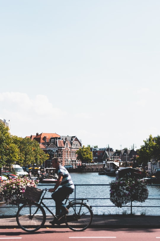 man in white shirt sitting on bench near river during daytime in Leiden Netherlands
