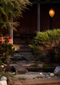 A serene backyard garden featuring a custom stone patio, manicured landscaping, and ambient outdoor lighting.