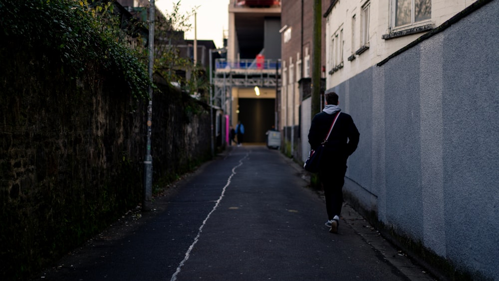 man in black jacket walking on sidewalk during daytime