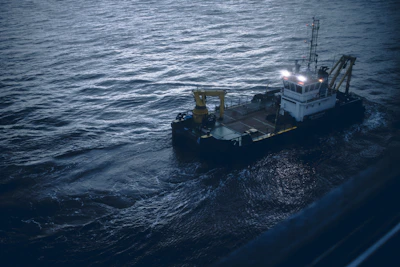 A powerful dredging vessel cutting through choppy ocean waters under a stormy sky.