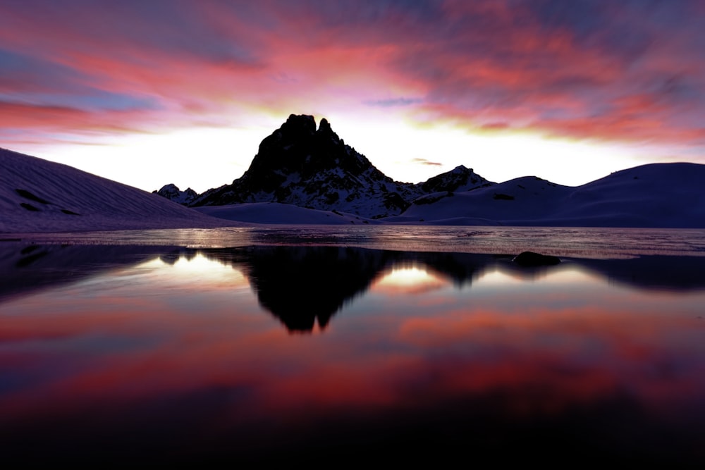 montagne enneigée près du lac au coucher du soleil