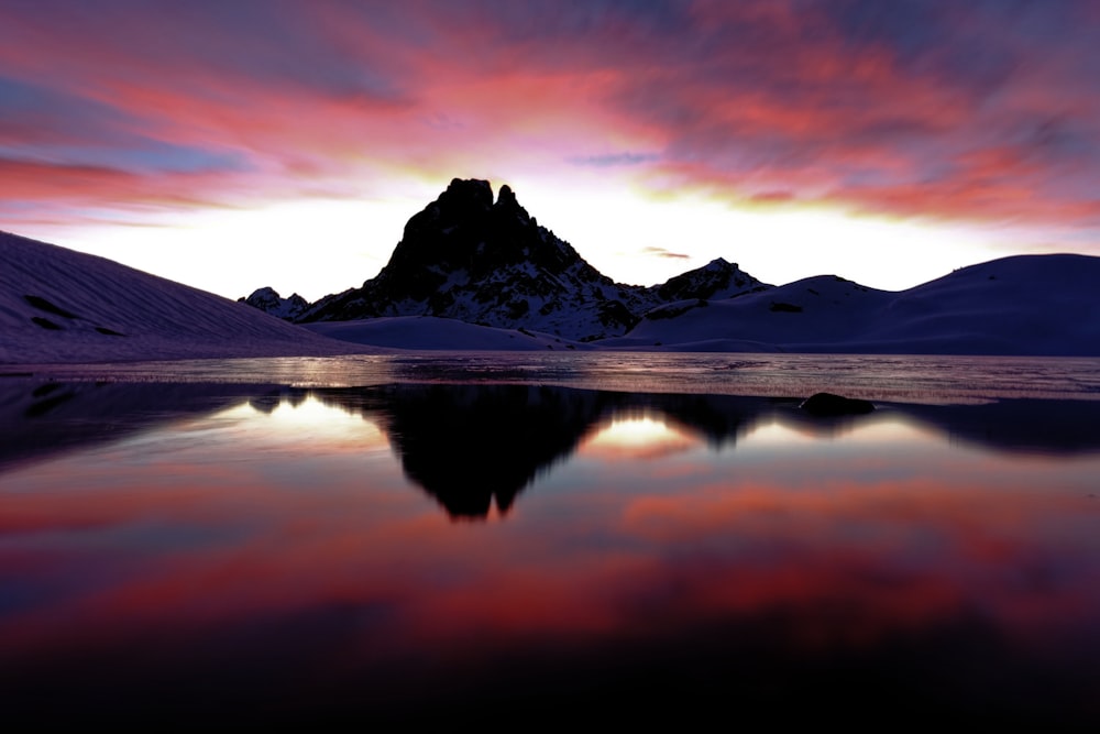 snow covered mountain near lake during sunset