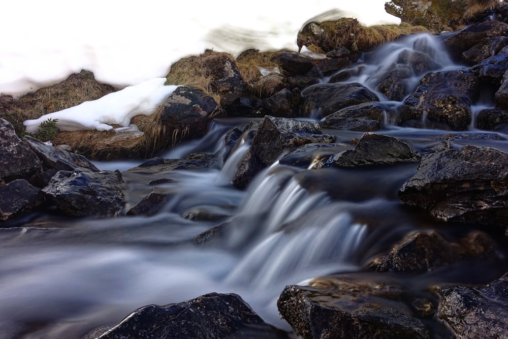 water falls on rocky shore during daytime