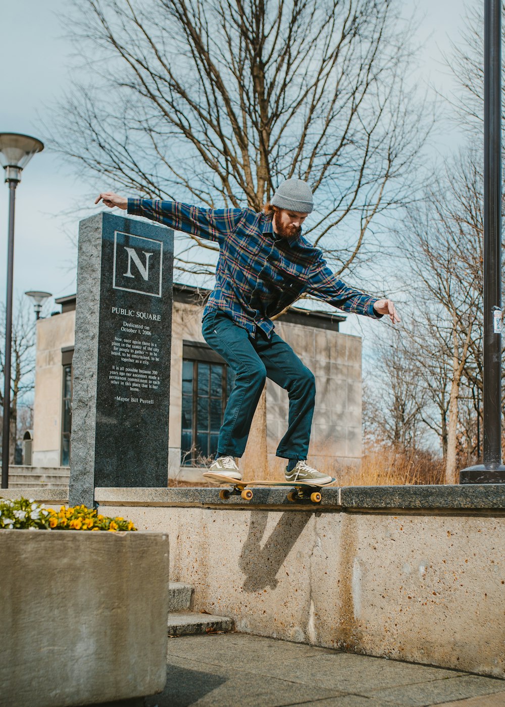 man in blue and black plaid dress shirt and blue denim jeans jumping on gray concrete