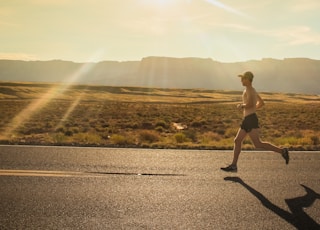 man in black shorts running on gray asphalt road during daytime