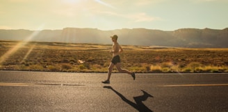 man in black shorts running on gray asphalt road during daytime