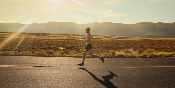 man in black shorts running on gray asphalt road during daytime