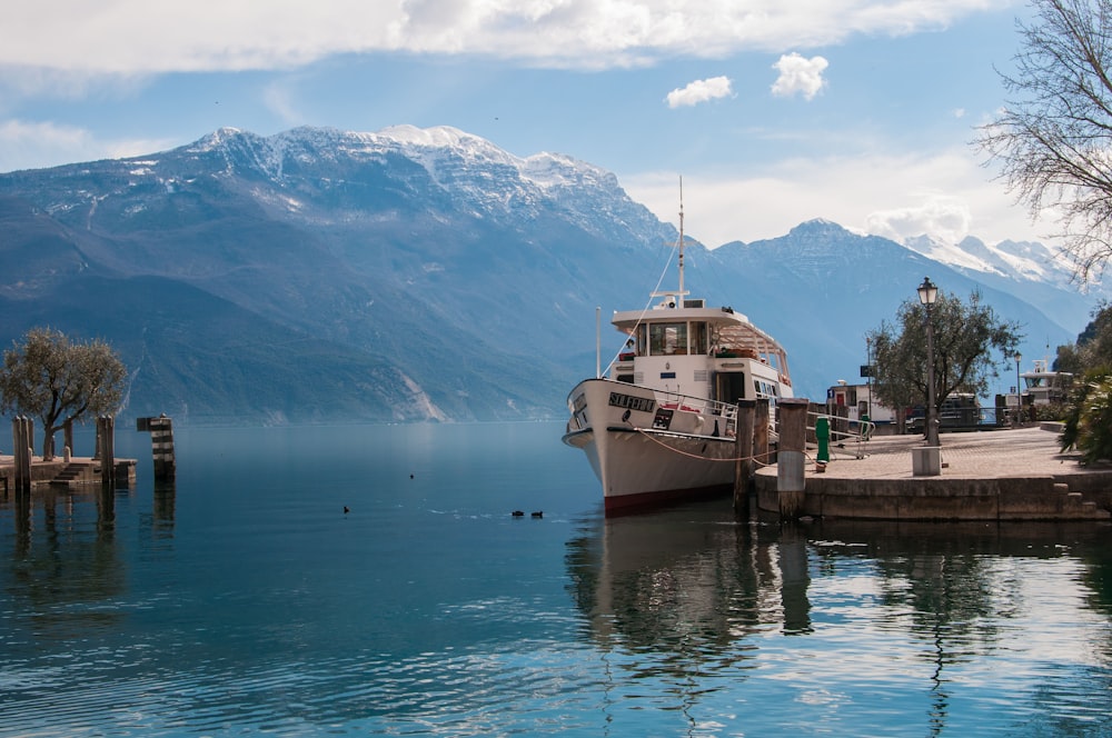 white and brown boat on water near mountain during daytime