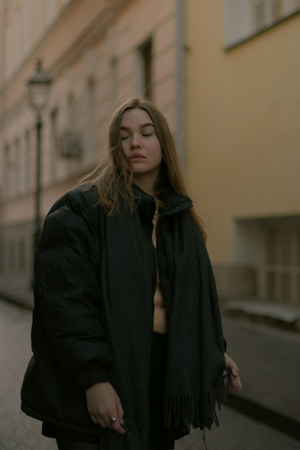 woman in black coat standing near brown wall