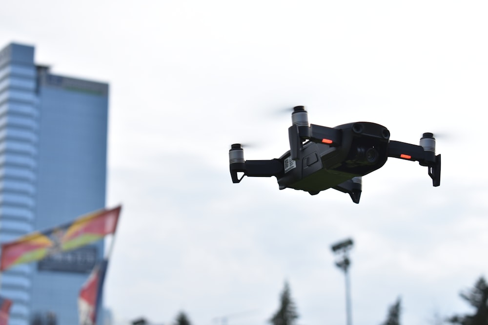 black drone flying in mid air during daytime