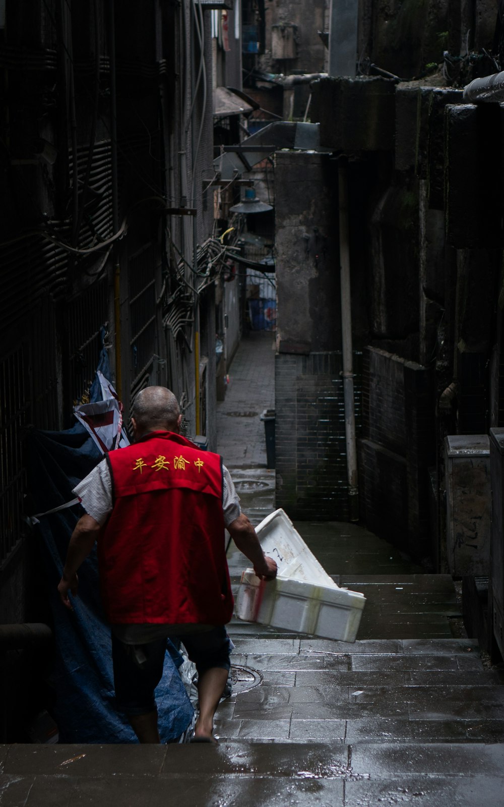 man in red shirt and blue denim jeans standing on sidewalk during daytime