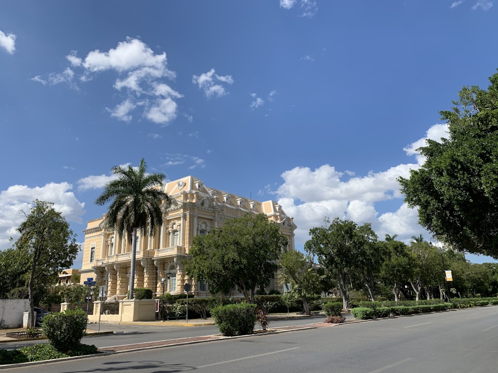 Palmeras verdes cerca de un edificio de hormigón blanco bajo el cielo azul durante el día