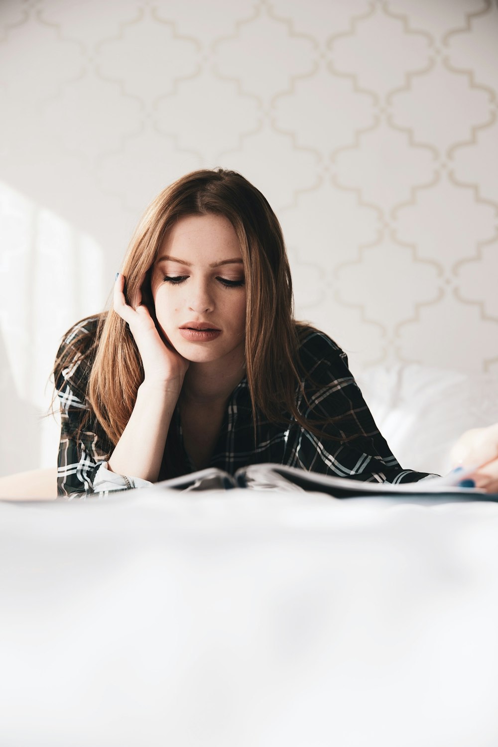 woman in black and white long sleeve shirt sitting on white bed