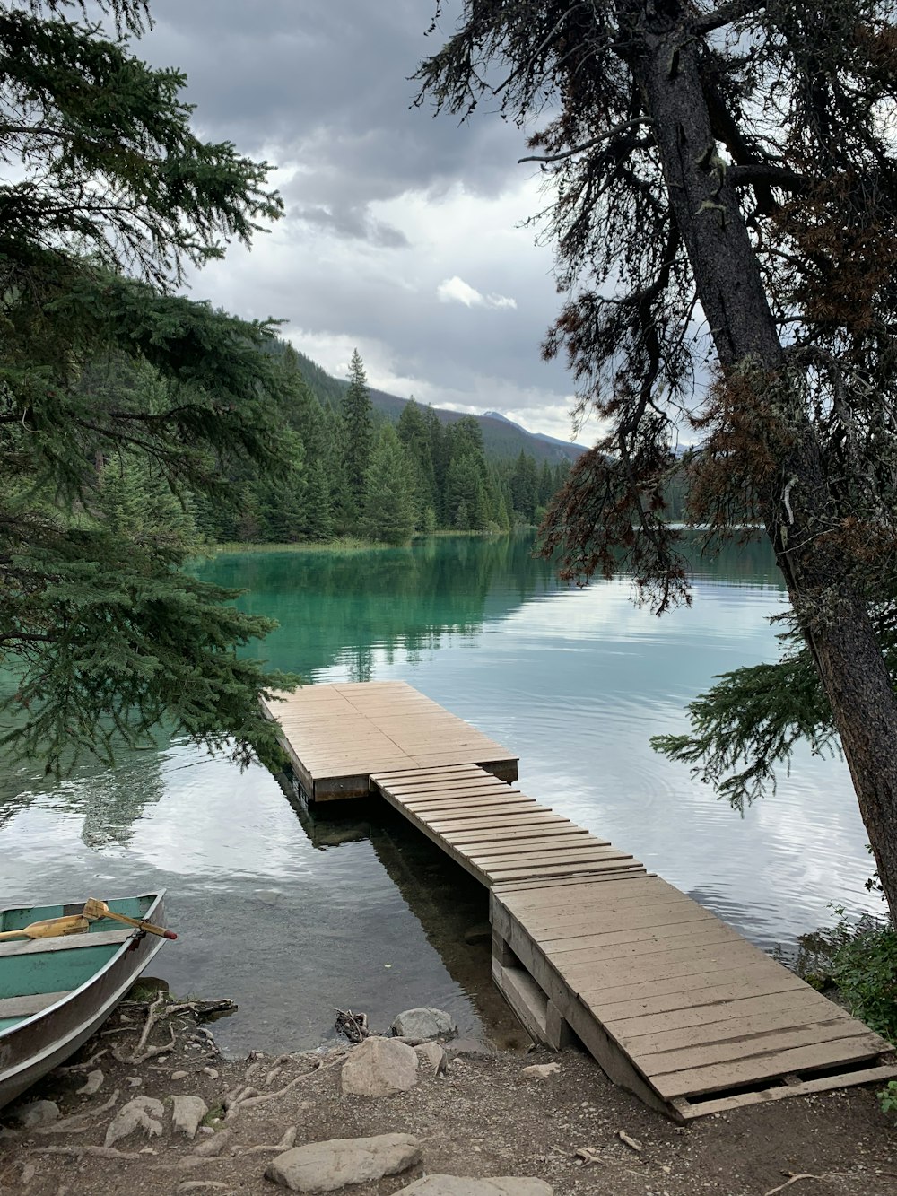 brown wooden dock on lake near green trees and mountains during daytime