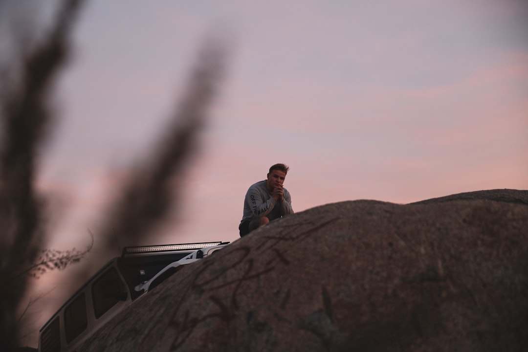 man in gray jacket sitting on top of car