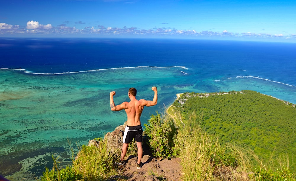 man in black shorts standing on green grass field near body of water during daytime