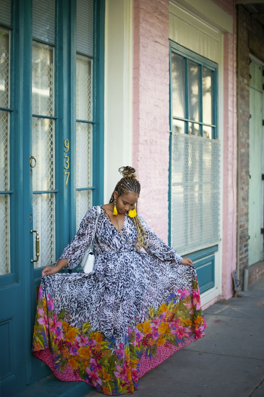 woman in blue and white floral dress sitting on blue wooden door during daytime