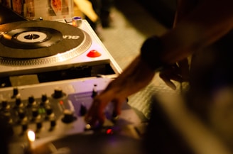 Close-up of a DJ mixing music on turntables in a dimly lit studio.