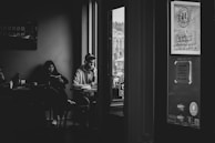 An intimate black-and-white photo of a playwright writing notes in a cozy café.