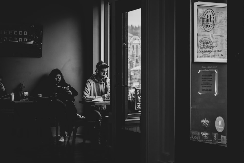 man in gray hoodie sitting on chair in front of window