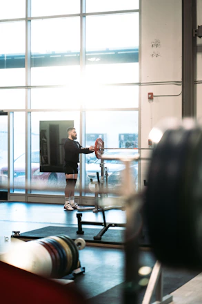 A focused man lifting weights in a sleek home gym with natural light.
