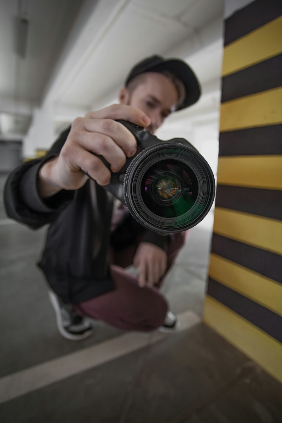 man in black and yellow striped long sleeve shirt holding black camera lens