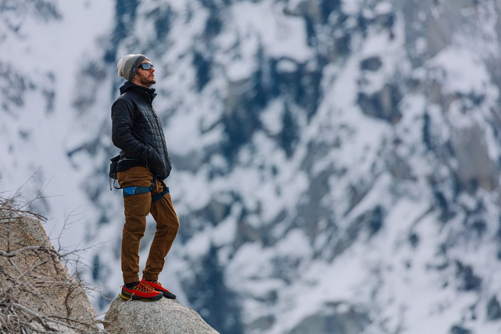 Foto Hombre con chaqueta negra y pantalones marrones de pie en la montaña  rocosa durante el día – Imagen Gris gratis en Unsplash