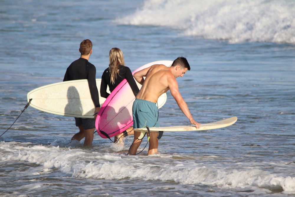 a group of people walking into the ocean with surfboards