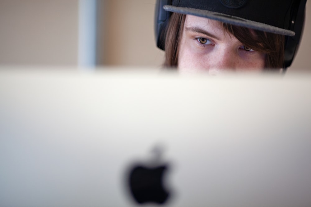 man in blue and black cap looking at silver imac