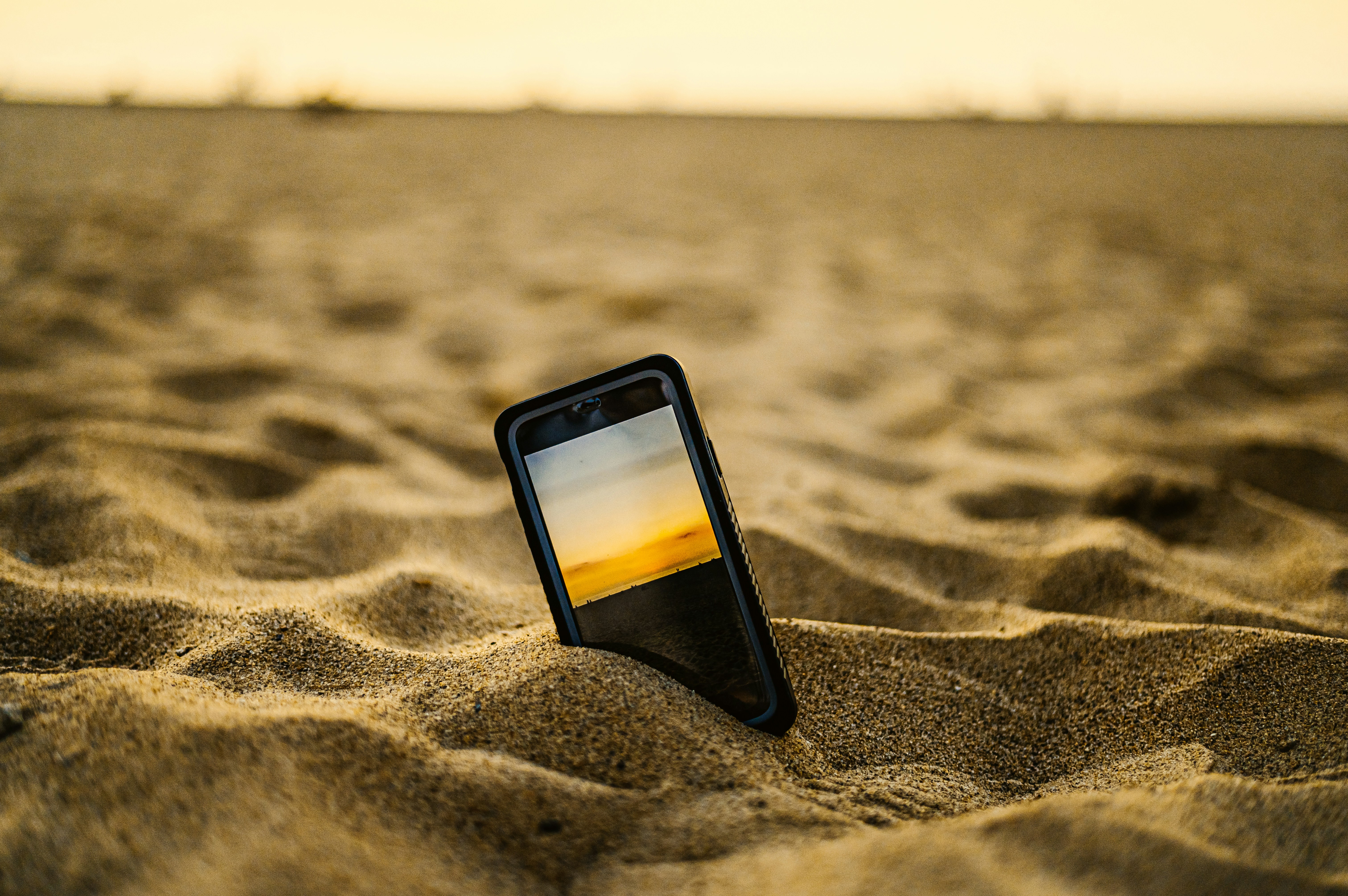 black iphone 5 on brown sand