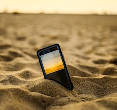 black iphone 5 on brown sand