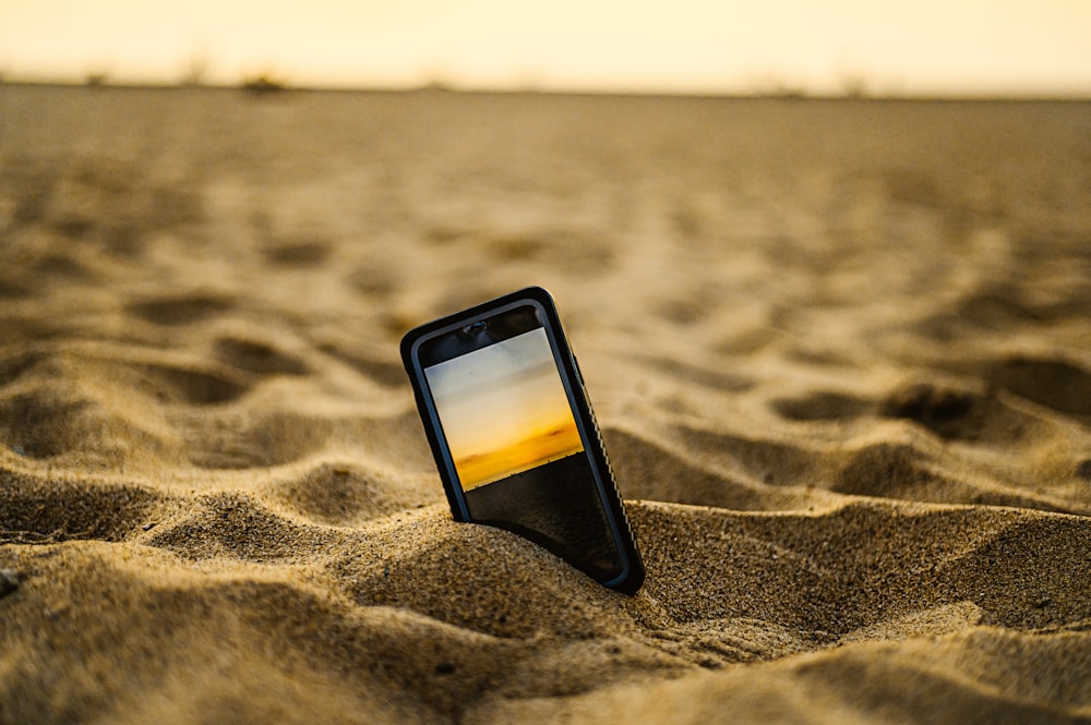 black iphone 5 on brown sand