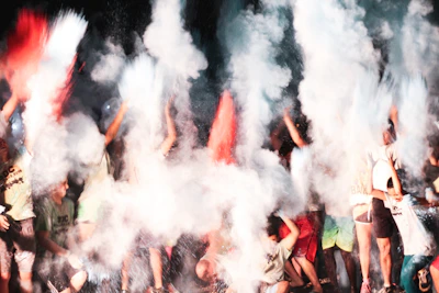 A lively scene of participants dancing with colorful powder clouds of purple and orange around them.