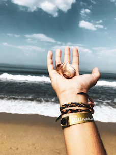 Close-up of delicate gold and navy bracelets on a textured beach towel by the sea
