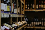 Rows of assorted wine bottles elegantly arranged on wooden shelves.