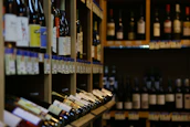 Bottles of wine lined up neatly on rustic wooden shelves behind the bar.