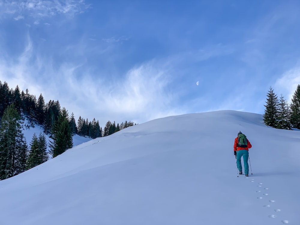 Persona con chaqueta roja y jeans de mezclilla azules caminando sobre suelo cubierto de nieve durante el día