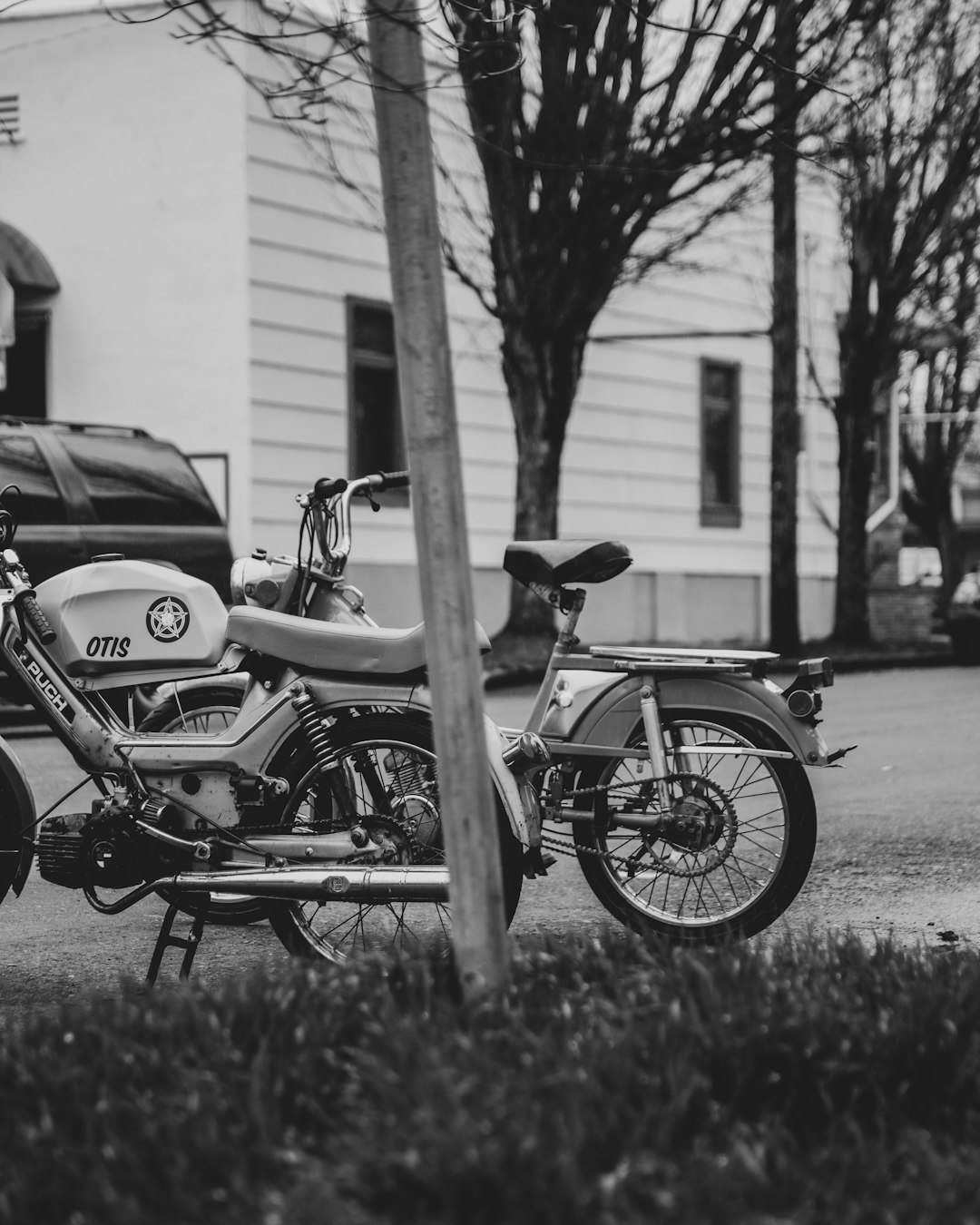 grayscale photo of motorcycle parked beside road