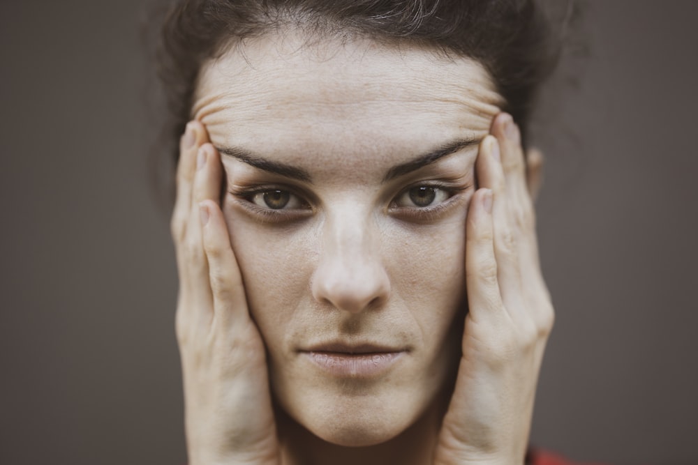 woman in red shirt covering her face with her hand