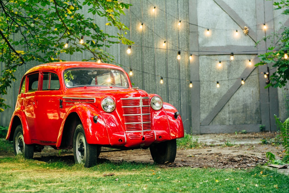 red vintage car parked beside gray wall