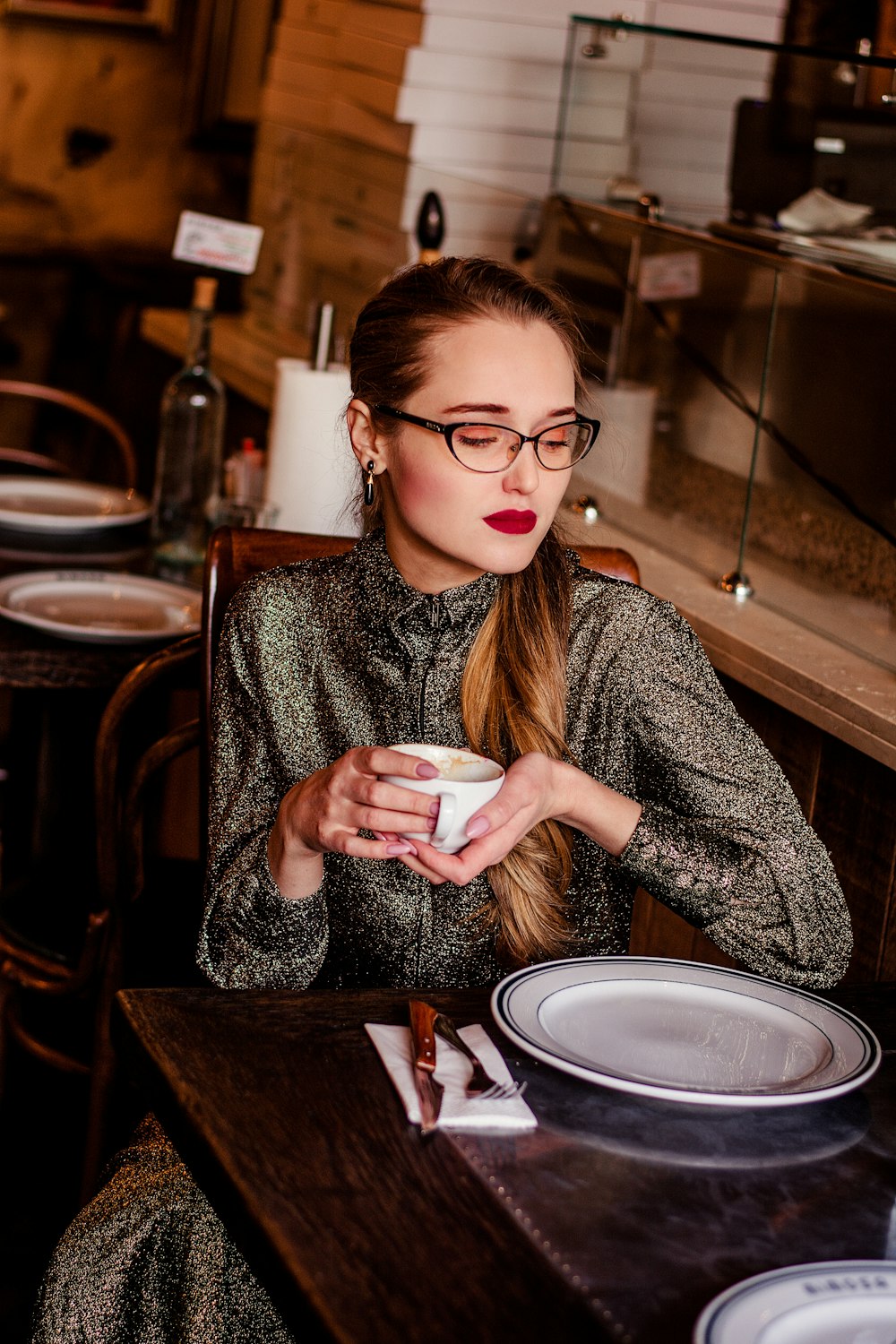 woman in gray sweater holding white ceramic mug