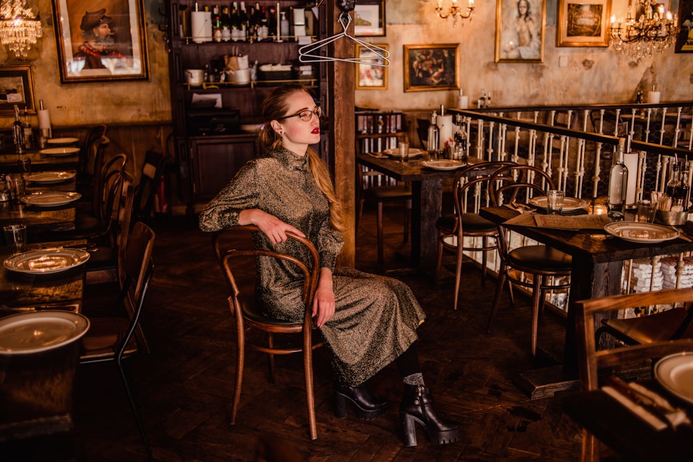 woman in black and white long sleeve dress sitting on brown wooden chair