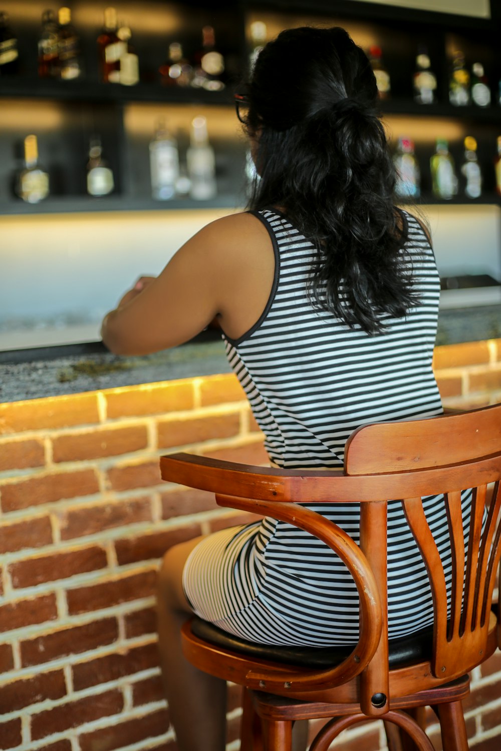 Femme en débardeur à rayures noires et blanches assise sur une chaise en bois marron