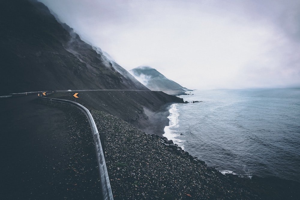 black asphalt road near body of water